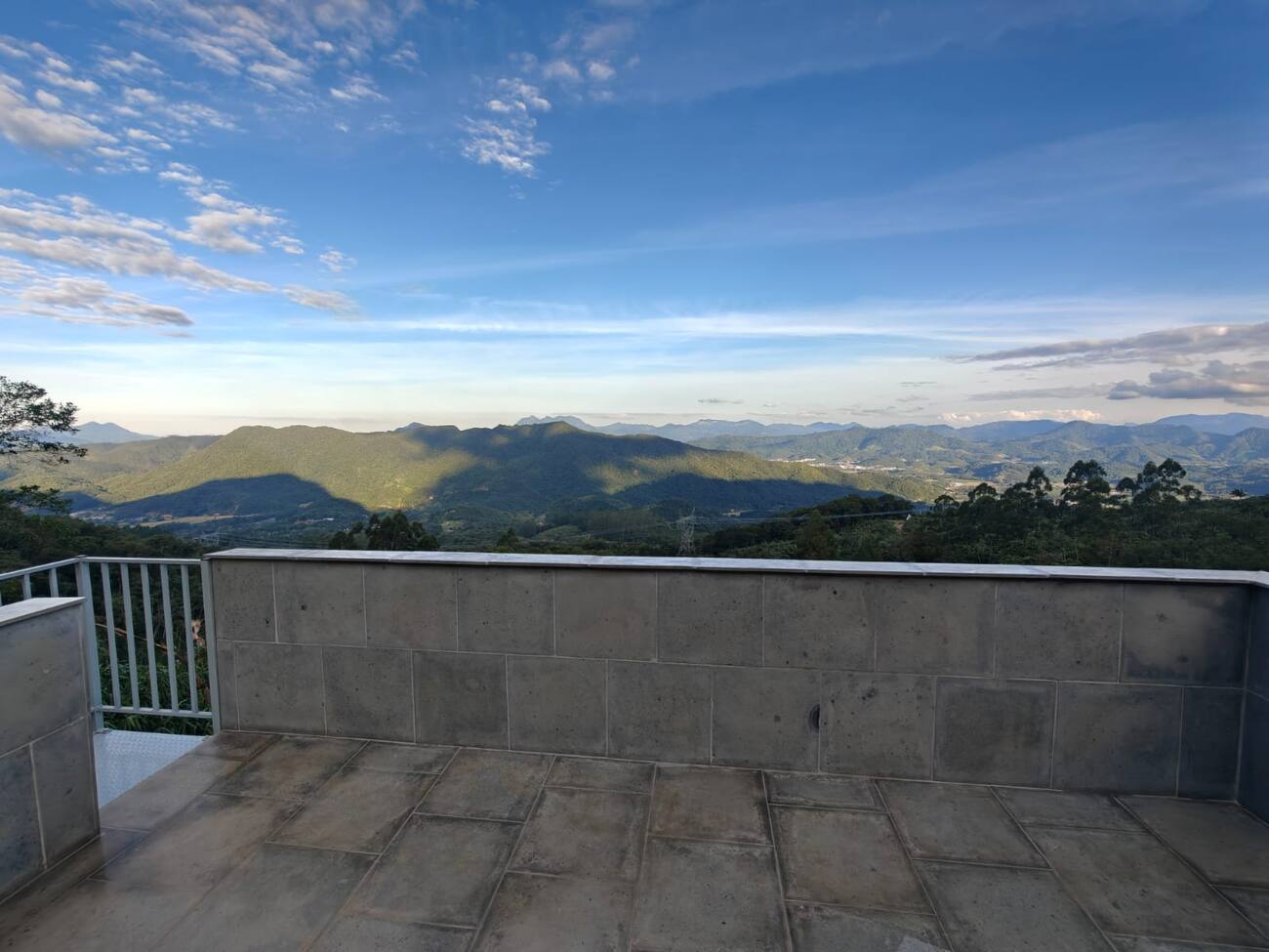 Vista do terraço da cobertura para as montanhas em camadas da Serra do Mar, ao entardecer.